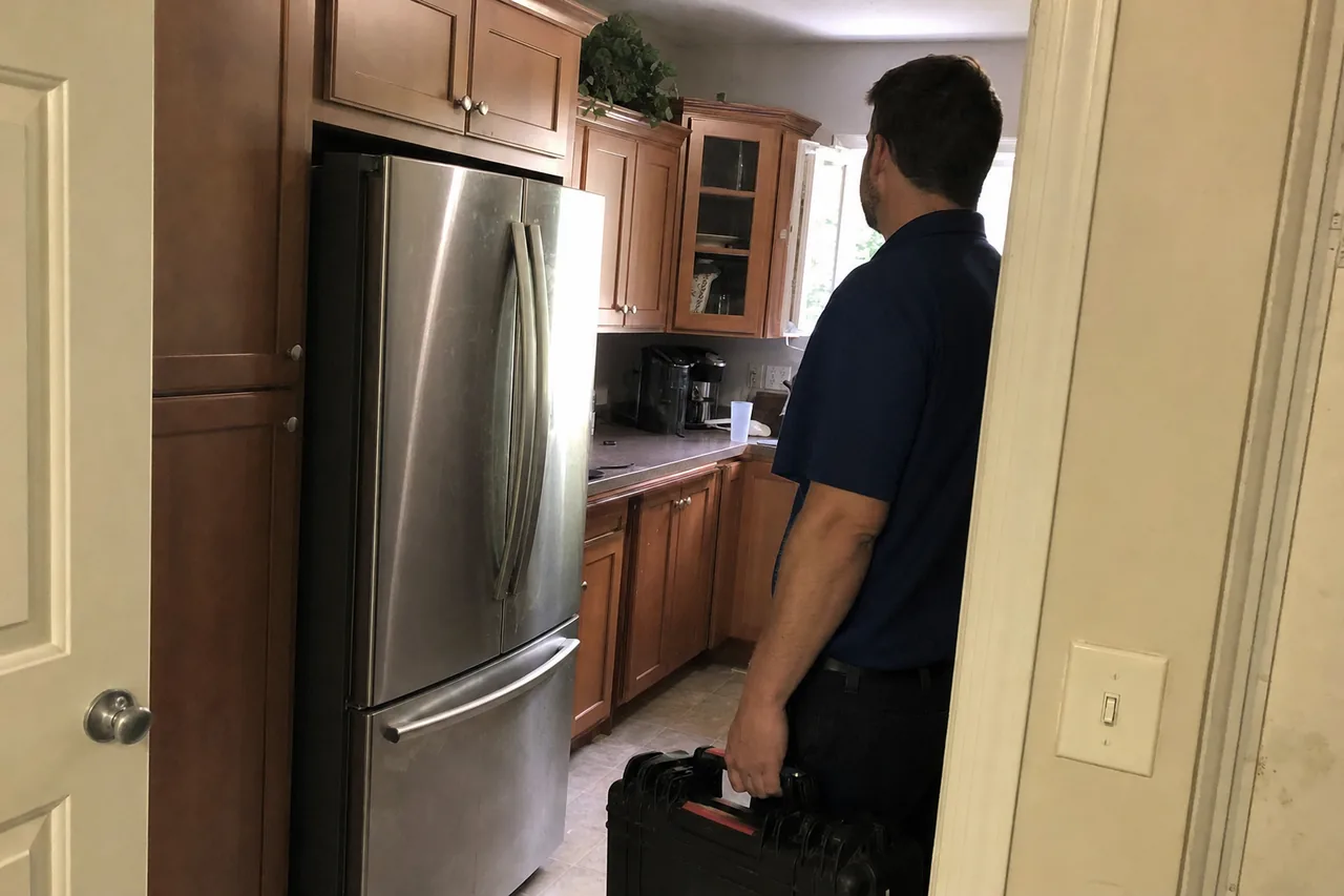 The same arrival seen from the other side of the doorway, wood cabinets and a stainless refrigerator beyond